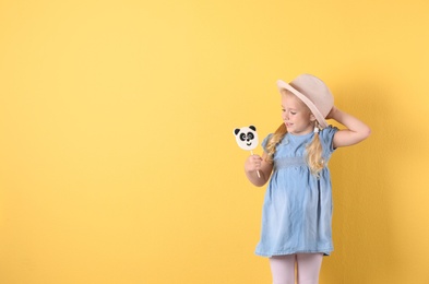 Photo of Cute little girl with candy on color background. Space for text