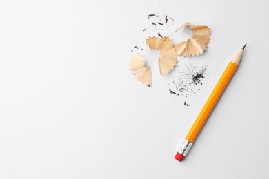 Photo of Graphite pencil and shavings on white background, flat lay. Space for text