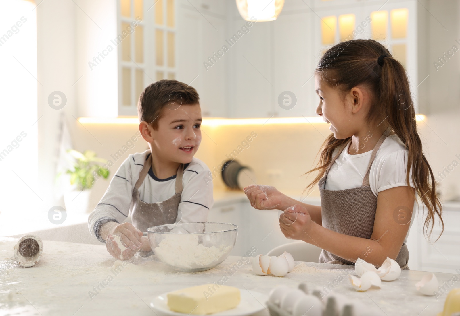 Photo of Cute little children cooking dough together in kitchen