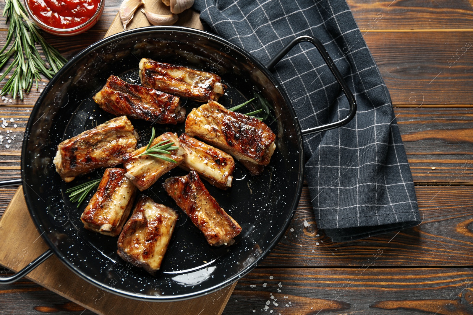 Photo of Delicious grilled ribs served on wooden table, flat lay