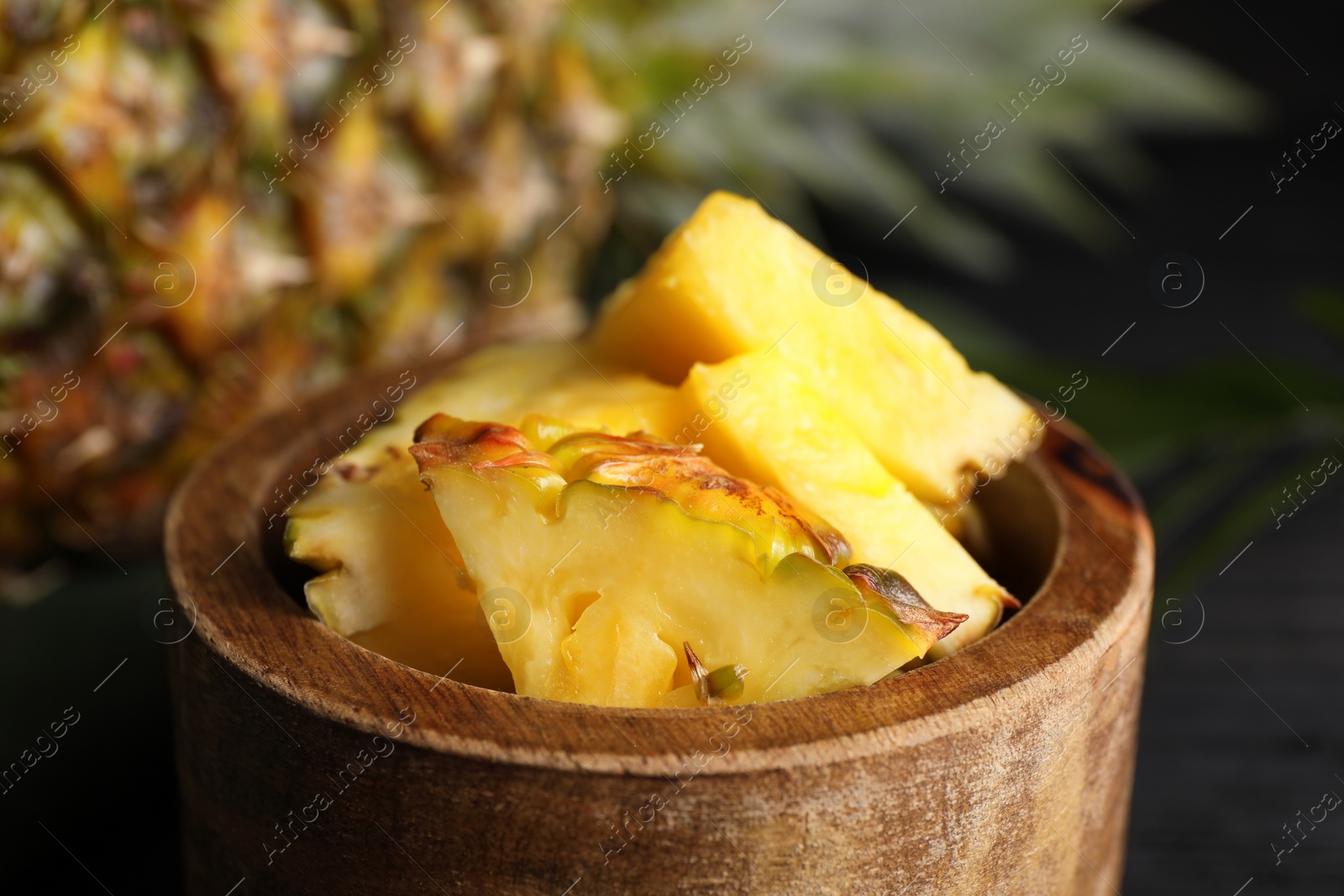 Photo of Pieces of tasty ripe pineapple in bowl on table, closeup