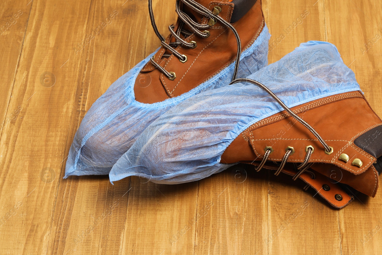 Photo of Men`s boots in blue shoe covers on wooden floor