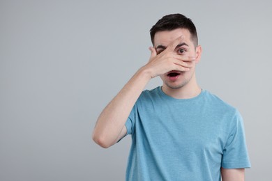 Photo of Embarrassed man covering face with hand on grey background. Space for text