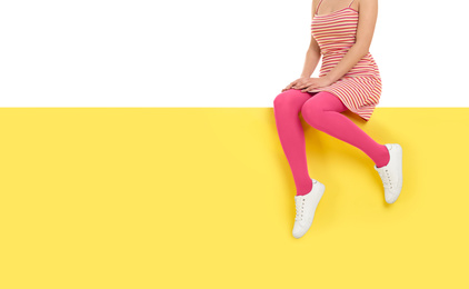 Photo of Woman wearing pink tights sitting on color background, closeup. Space for text