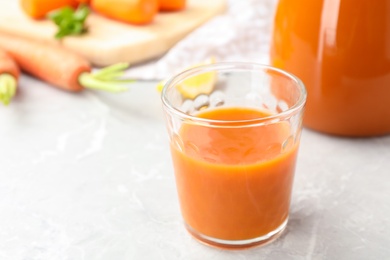 Photo of Glass of carrot drink on light table, space for text