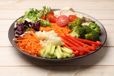 Photo of Balanced diet and healthy foods. Plate with different delicious products on light wooden table, closeup