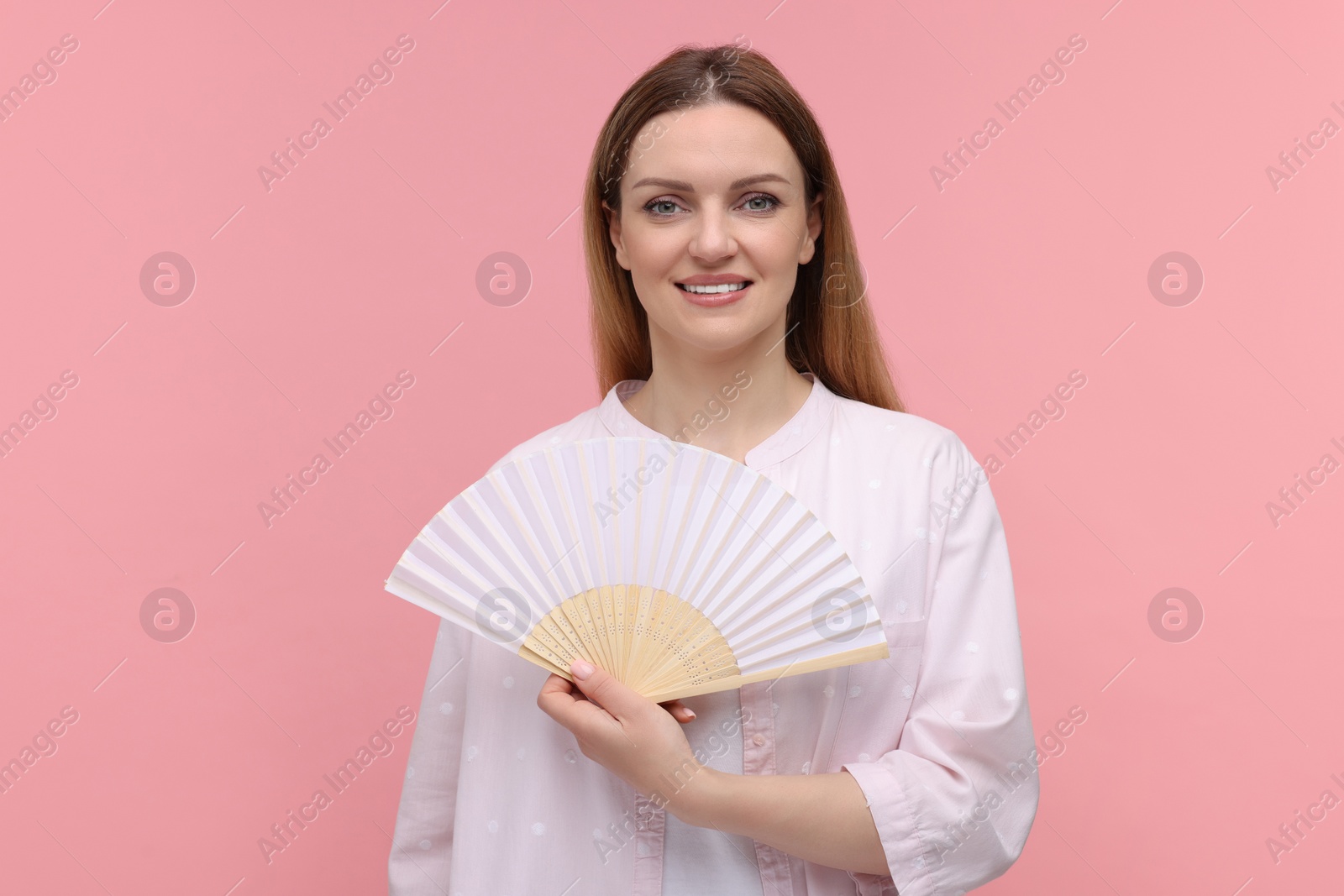 Photo of Happy woman with hand fan on pink background