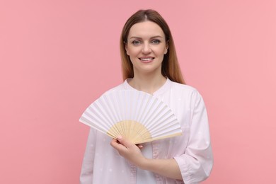 Happy woman with hand fan on pink background