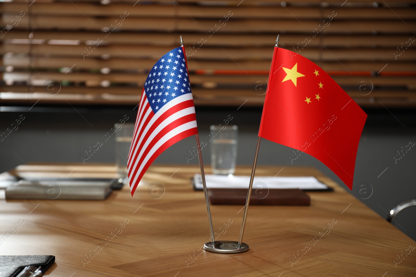 Photo of USA and China flags on wooden table in office. International relations