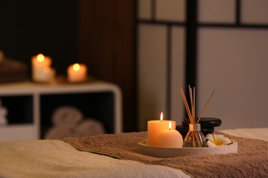 Photo of Burning candles and aromatic reed freshener on table in spa salon, space for text