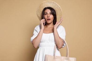 Photo of Young woman with stylish bag and smartphone on beige background