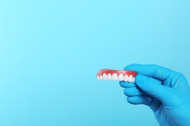 Photo of Dentist holding teeth cover on color background. Space for text
