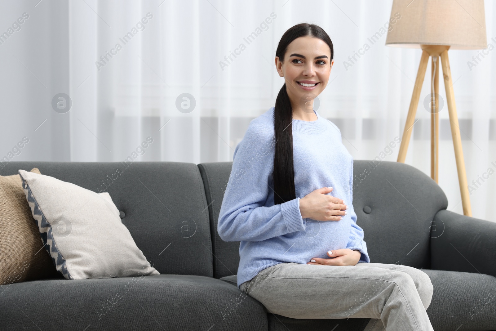 Photo of Happy pregnant woman on sofa at home