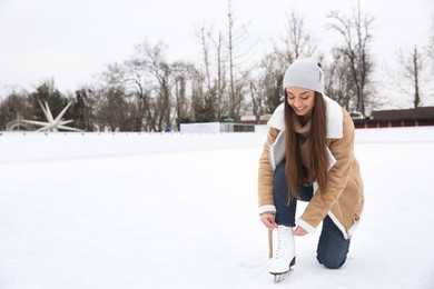 Image of Woman lacing figure skate on ice rink. Space for text