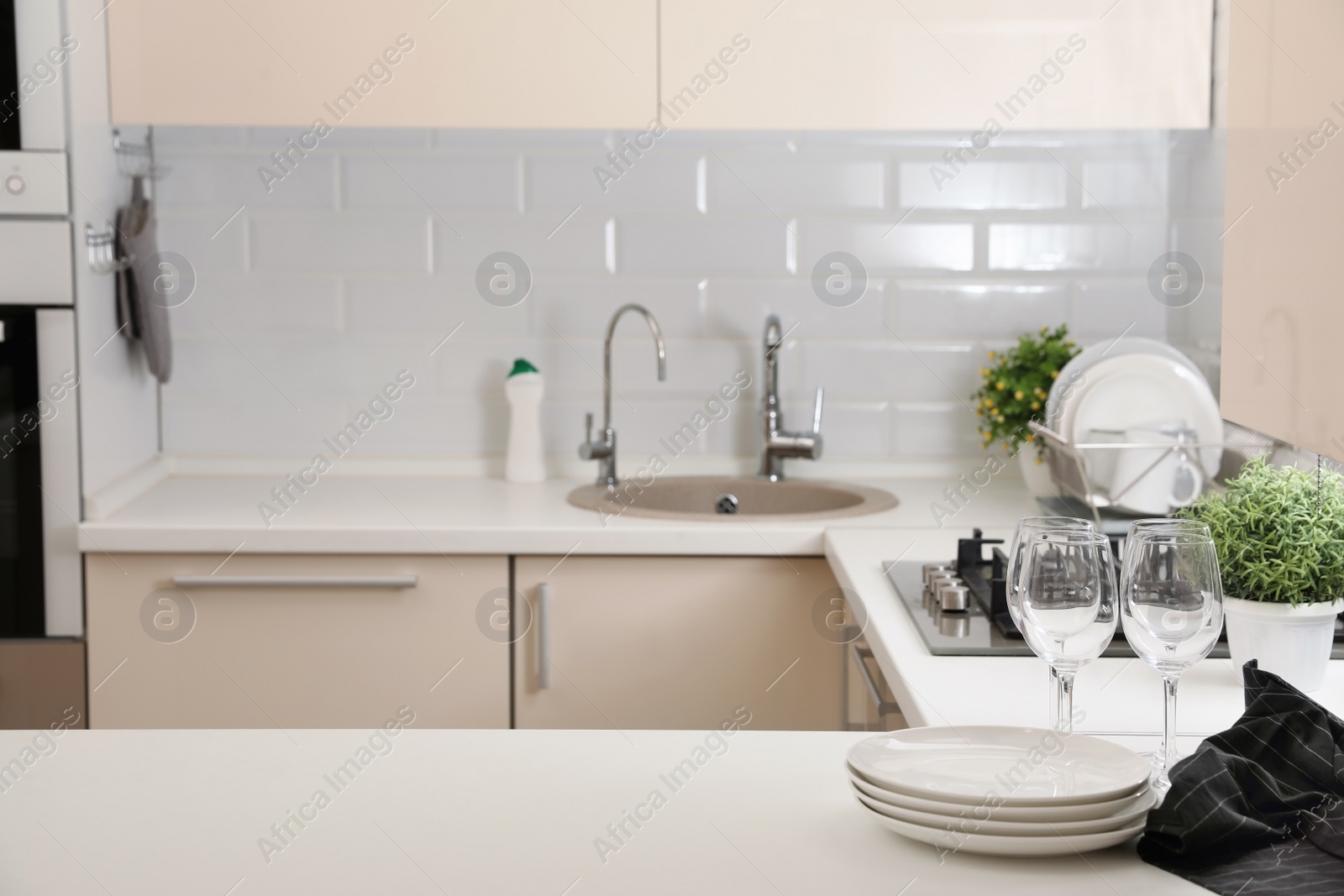 Photo of Stack of clean dishes and glasses on table in kitchen. Space for text