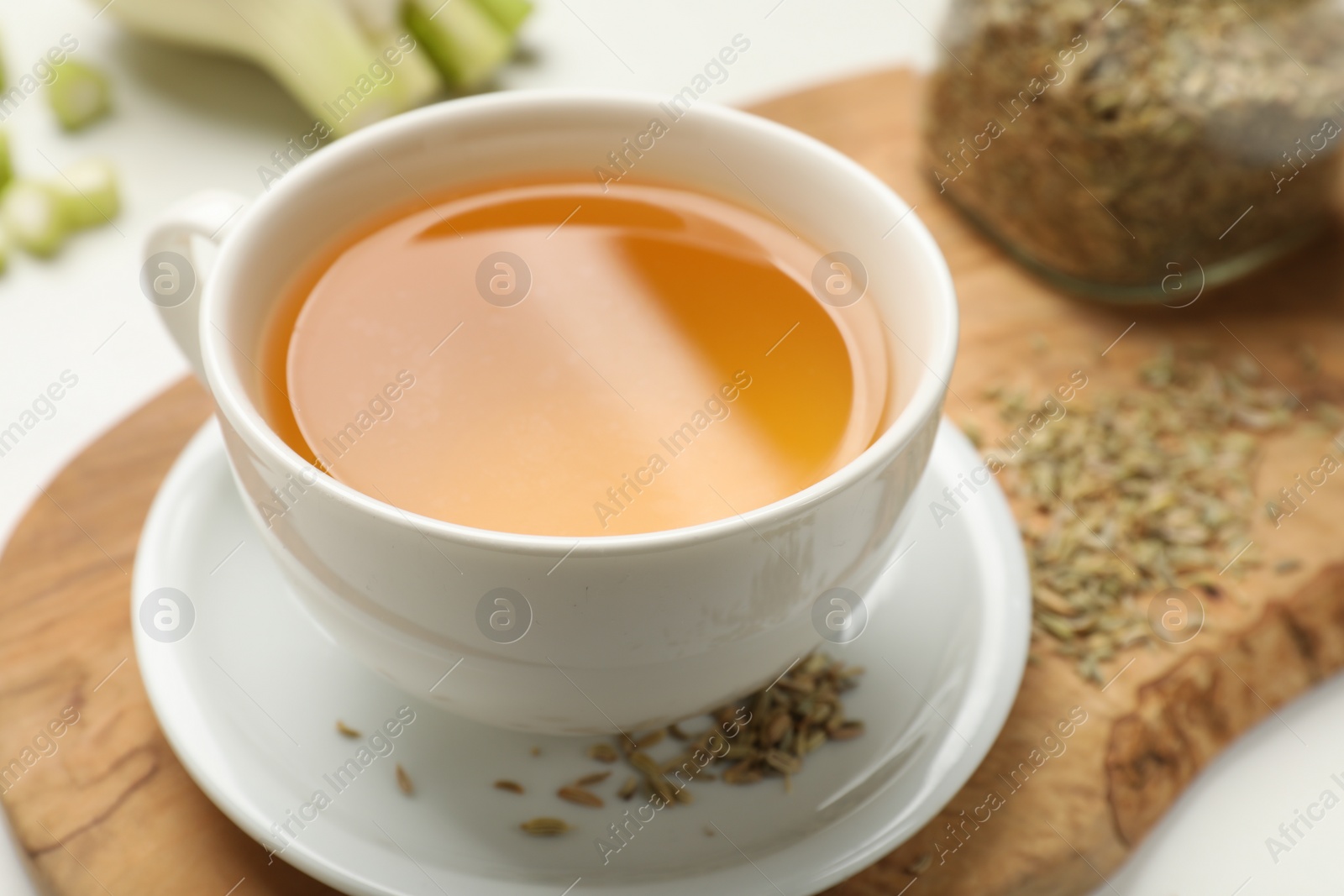 Photo of Fennel tea in cup and seeds on white table, closeup