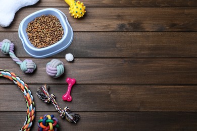 Different pet toys and feeding bowl on wooden background, flat lay. Space for text