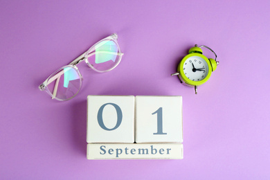 Photo of Calendar, glasses and alarm clock on violet background, flat lay