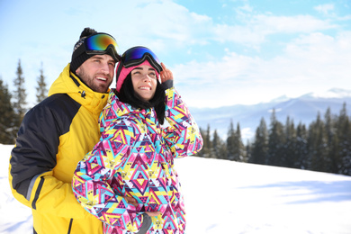 Photo of Young couple at ski resort, space for text. Winter vacation