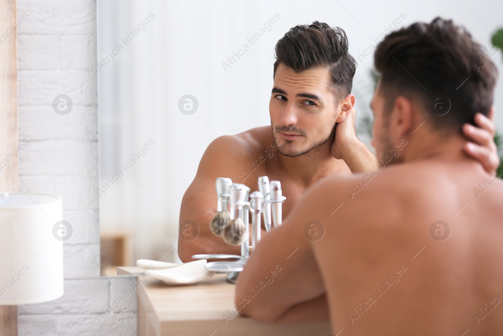 Photo of Young man with stubble ready for shaving near mirror in bathroom