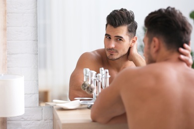 Photo of Young man with stubble ready for shaving near mirror in bathroom