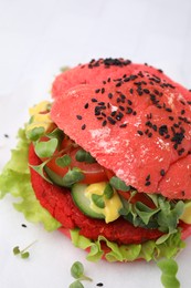 Tasty pink vegan burger with vegetables, patty and microgreens on white table, closeup