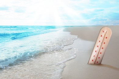 Thermometer in sand on beach during sunny summer day