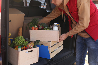 Courier taking crate with products from car, closeup. Food delivery service