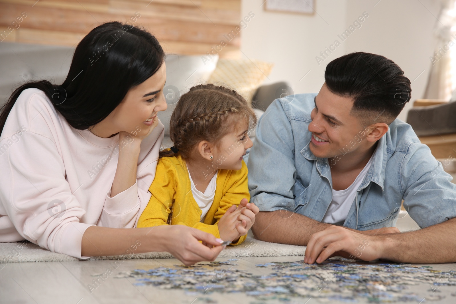 Photo of Happy family playing with puzzles on floor at home