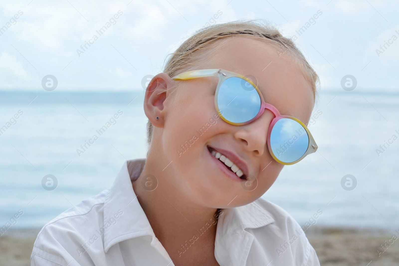 Photo of Little girl wearing sunglasses at beach on sunny day