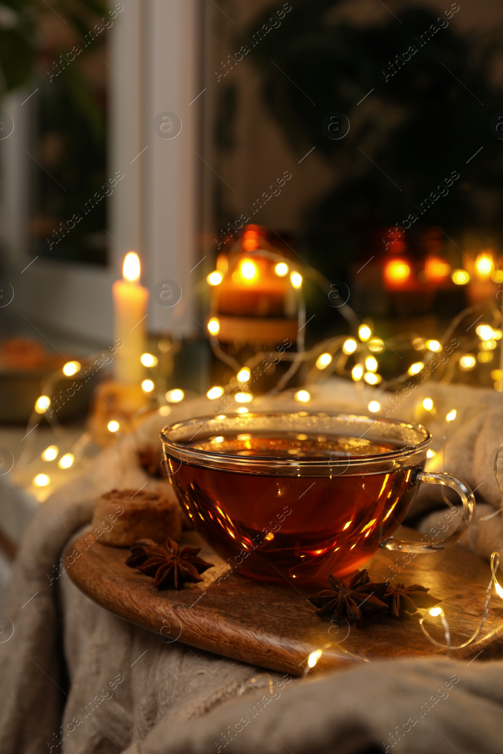 Photo of Glass cup of aromatic anise tea on wooden board indoors, bokeh effect