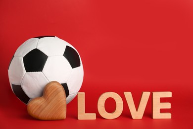 Photo of Soccer ball, word Love and heart on red background. Space for text