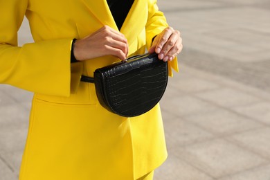 Young woman with stylish waist bag outdoors, closeup