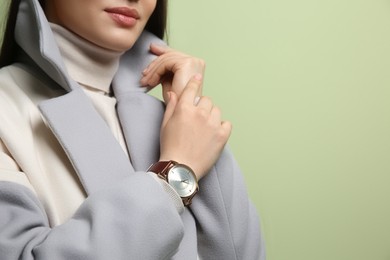 Woman with luxury wristwatch on green background, closeup. Space for text