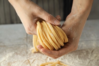 Photo of Woman with homemade pasta at light tiled table, closeup