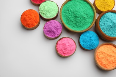 Colorful powders in bowls on light background, flat lay with space for text. Holi festival celebration