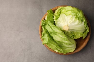 Photo of Bowl with fresh green iceberg lettuce head and leaves on grey table, top view. Space for text