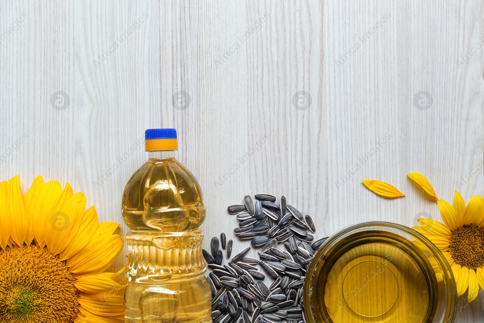 Photo of Flat lay composition with sunflower oil on light wooden table, flat lay. Space for text