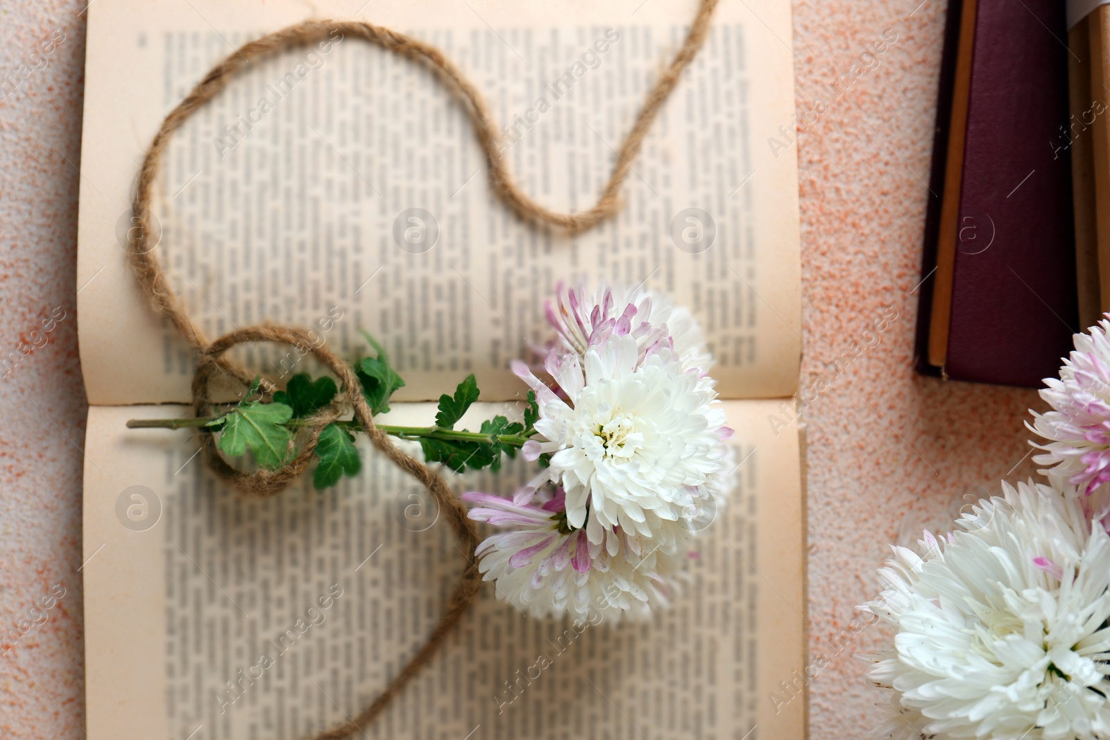 Photo of Book with chrysanthemum flowers as bookmark on beige textured background, flat lay