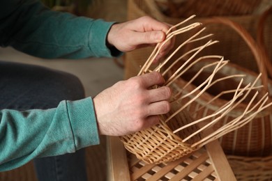 Man weaving wicker basket indoors, closeup view