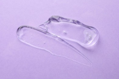 Clear cosmetic gel on violet background, top view