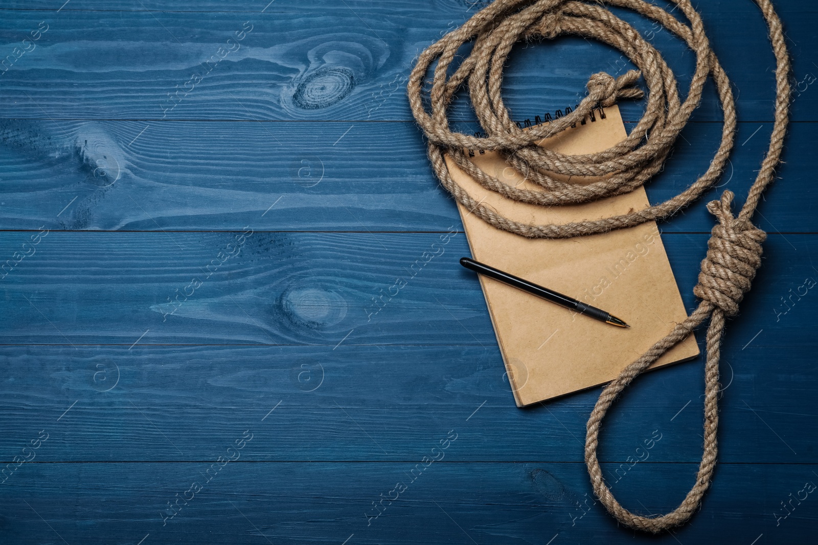 Photo of Rope noose and blank notebook with pen on blue wooden table, flat lay. Space for text