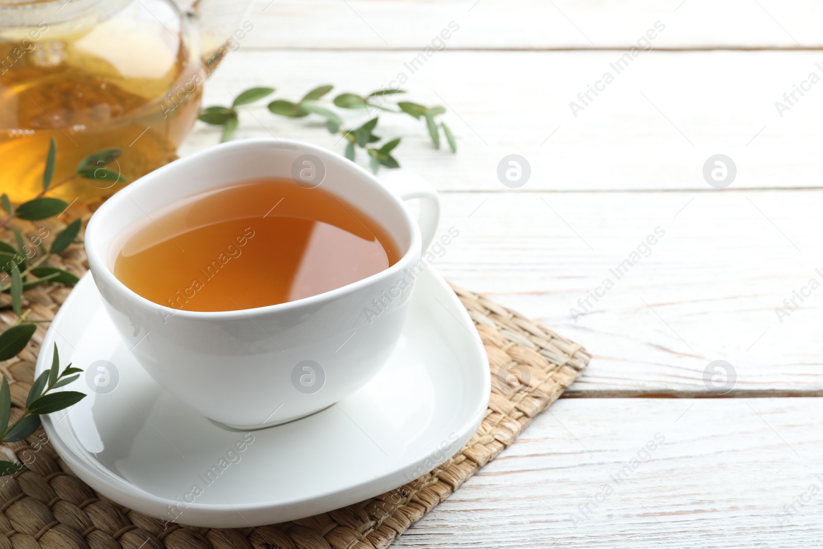 Photo of Cup of aromatic eucalyptus tea on white wooden table. Space for text