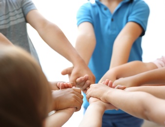 Photo of Little children holding their hands together on light background. Unity concept