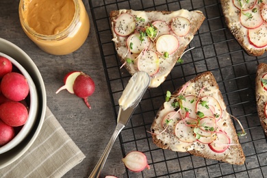 Photo of Tasty toasts with radishes, sprouts and chia seeds served on table, top view