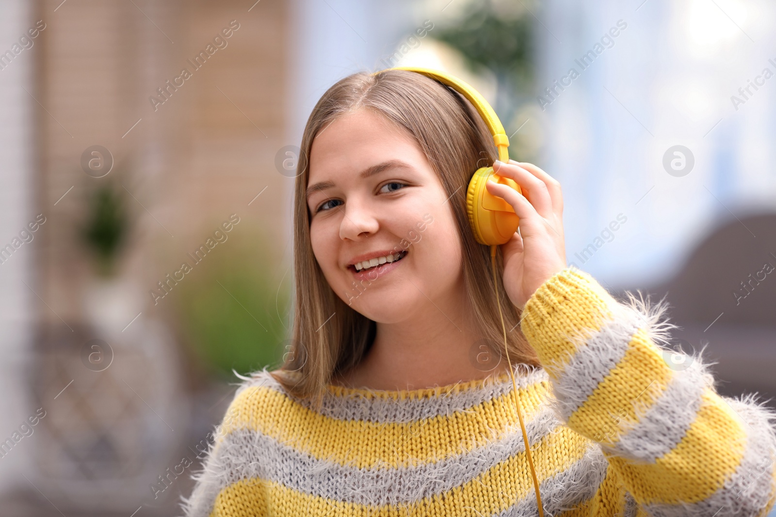 Photo of Happy teenage girl listening to music with headphones at home