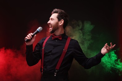 Emotional man with microphone singing in color lights