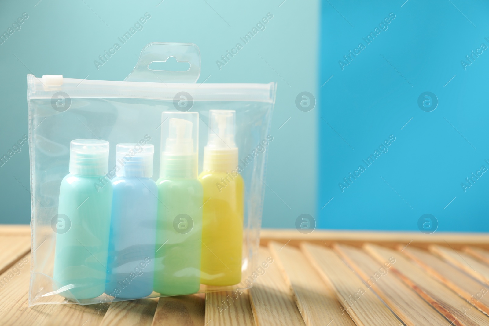 Photo of Cosmetic travel kit in plastic bag on wooden table, space for text. Bath accessories