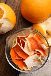 Photo of Dry peels and oranges on wooden table, flat lay