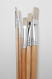 Different paint brushes on white background, top view